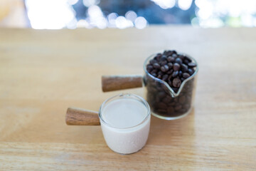 Coffee grains in mini glass cup and fresh milk in cup. Preparing fresh coffee at cafe