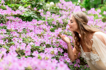 A beautiful pregnant woman near a blooming rhododendron bush