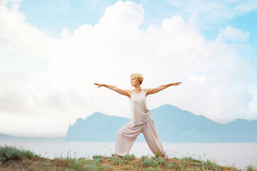 Senior woman doing yoga exercises with mountain on the background