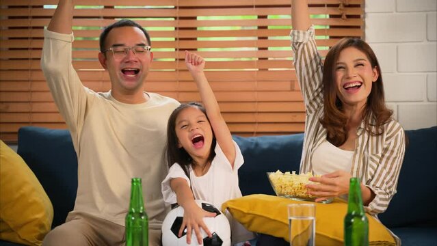 Happy family watching sports match together on television