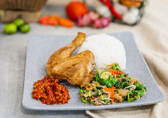 Bebek Goreng Lalapan or Fried duck, One of Indonesia's culinary icons on decorated background with rice and vegetables