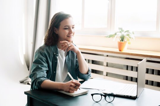 Young woman multitasking with laptop computer at office and student girl working remotely from home. Online work, study, freelance, and modern office lifestyle concept.