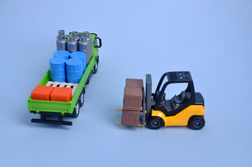 caminhão de brinquedo carregado com empilhadeira ao lado em fundo azul 