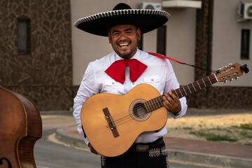 Mexican musician mariachi plays the guitar on a city street.