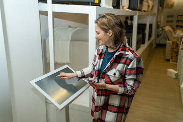 Woman uses the self-service kiosk in the store..