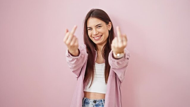 Young beautiful hispanic woman smiling confident doing middle finger gesture over isolated pink background