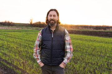 Naklejka na ściany i meble Portrait of bearded farmer on a field at sunset..