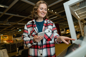 Woman uses the self-service kiosk in the store..