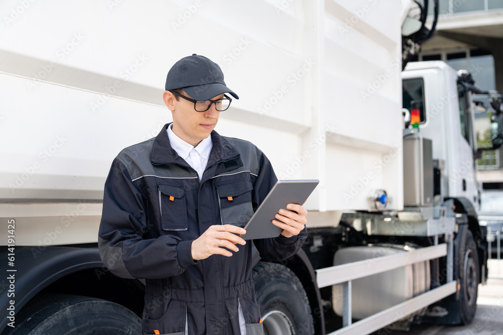 Poster Manager with a digital tablet next to garbage truck..