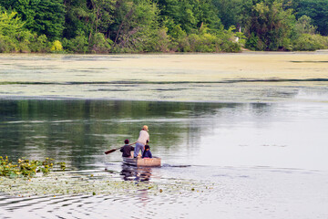 Fototapeta na wymiar Amish dad and kids in row boat on lake in summer.