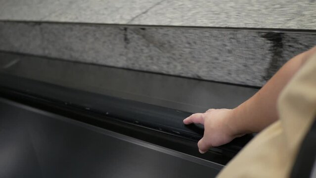 movement of the Business person man's hand on the escalator handrails while getting down to the subway train station terminal in 4k close-up style