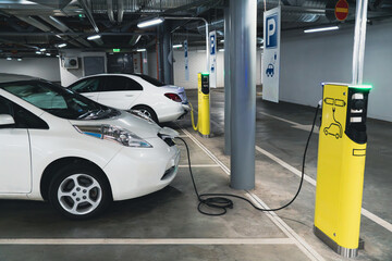 Fototapeta na wymiar Electric cars are charged from the charging station in the indoor parking of the shopping center.