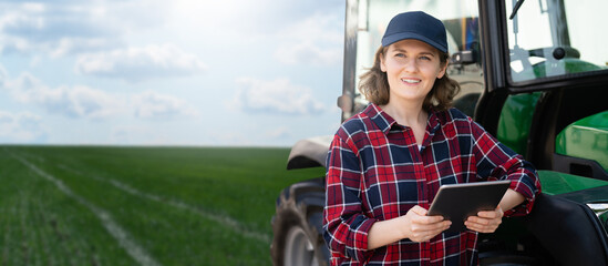 Woman farmer with a digital tablet next to agricultural tractor © scharfsinn86