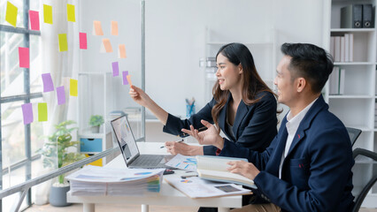 Two Young Asian business people discuss with new startup project Idea presentation, analyze planning and financial statistics and investment market at office.