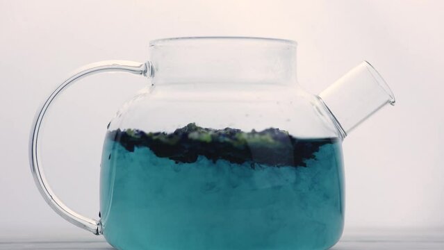 Blue tea is infused in a glass teapot. A healthy herbal drink for detoxification
