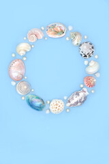 Seashell and oyster pearl wreath decoration. Summer garland with collection of assorted shells and pearls on blue background. Circular natural nature design, beach and seaside art.