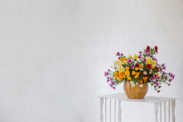 Fototapeta na wymiar bouquet of colorful chrysanthemums in vase on background white old wall