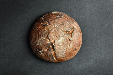 Homemade black bran round bread. Fresh bread on a black background. Top view.