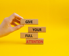 Give your full Attention symbol. Concept word Give your full Attention on wooden blocks. Beautiful yellow background. Businessman hand. Business and Give your full Attention concept. Copy space