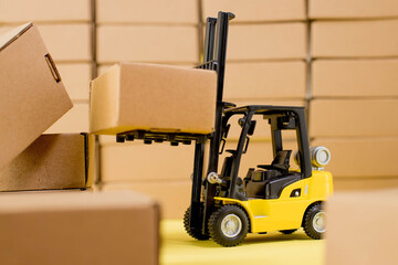 Forklift truck raises cardboard boxes on a yellow background. Cargo sorting concept