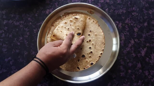 A delightful homemade roti, chapati, or flatbread is folded by a male hand