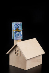 A symbolic wooden house and a bundle of 10,000 Kazakhstani tenge banknotes