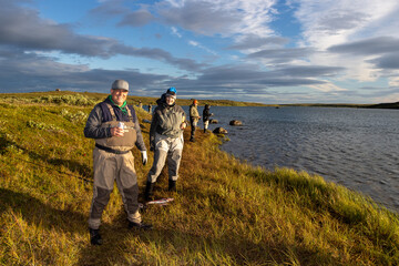 Happy people fishing in Alaska during the early morning