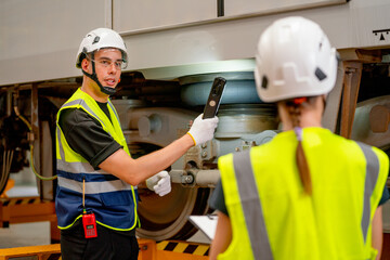 Professional technician hold light stick and discuss to his co-worker to the problem of part of electric train in workplace area.