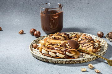 Homemade thin crepes with chocolate spread, banana and hazelnuts. breakfast or dessert. banner, menu, recipe place for text, top view
