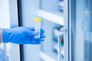 Medical scientist wearing blue gloves holding blood test tube in medical laboratory.Chemistry...