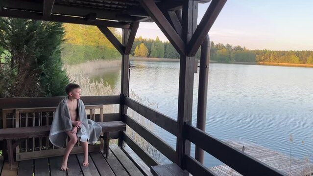 A boy on a beautiful terrace or gazebo on the shore of a beautiful lake.