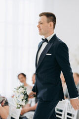 groom waiting for a bride with a bouquet walking on a podium