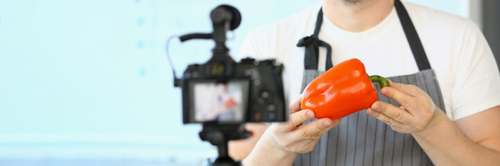 Food blogger creates healthy eating content and videos. Chef holds red pepper in hands and points to camera