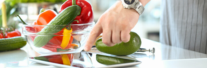 Chef following recipe on digital tablet preparing vegetable salad in kitchen. Online cooking course...