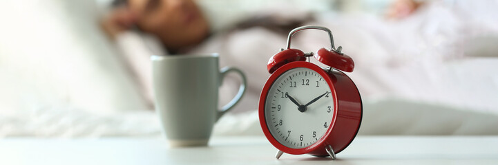 Red alarm clock at ten o'clock and sleeping woman. Peaceful sleep and late rise concept
