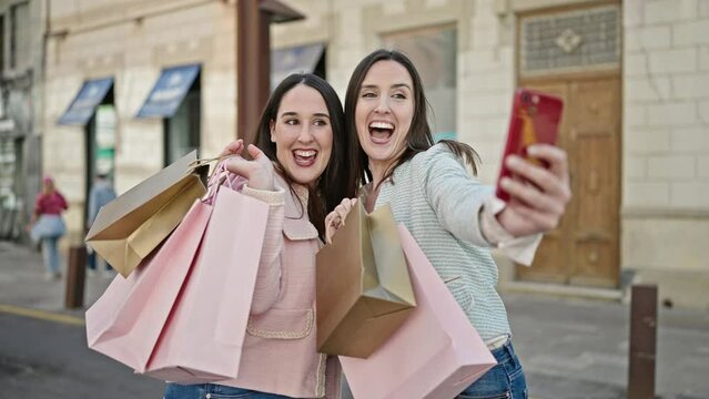 Two women going shopping holding bags make selfie by smartphone at street