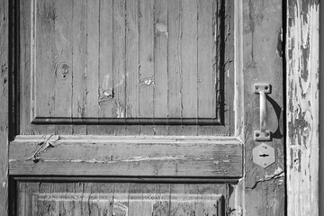 An old dilapidated wooden door with a handle. The front door is old, abandoned.