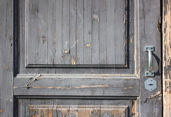 An old dilapidated wooden door with a handle. The front door is old, abandoned.