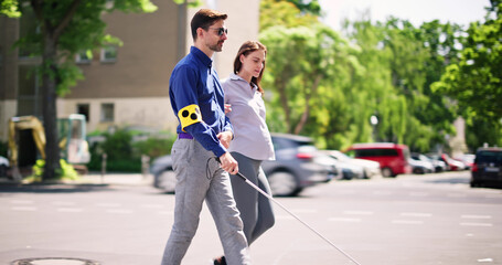 Young Woman Helping Blind Man With White Stick