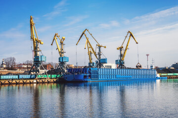 Sea port with cranes, barge and railway carriages.