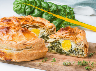 Torta pasqualina made with yellow chard. One slice is cut out and has the egg exposed.