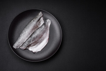 Raw sea bass fish fillet with salt, spices and herbs on a ceramic plate - obrazy, fototapety, plakaty