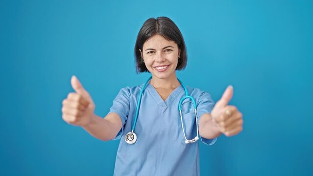 Young beautiful hispanic woman doctor doing thumbs up over isolated blue background