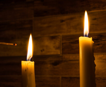Candles burn with a yellow flame, a match ignites the flame