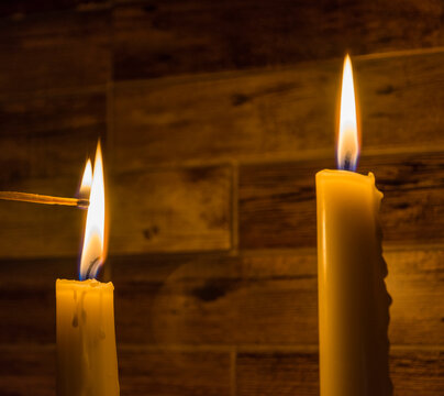 Candles burn with a yellow flame, a match ignites the flame
