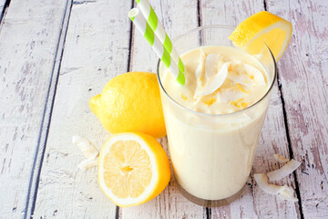 Summer lemon coconut smoothie. Close up table scene with a white wood background.