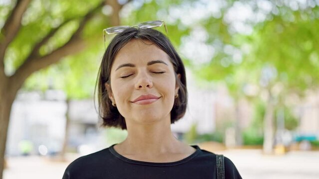 Young beautiful hispanic woman smiling confident breathing at park