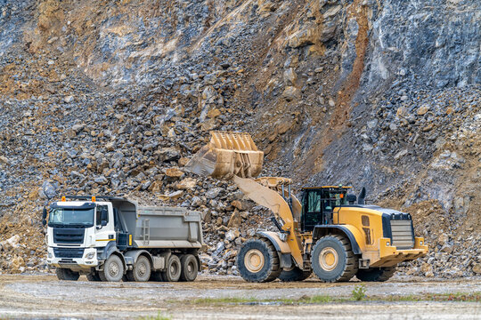 an excavator is loading a truck with stone at a quarry