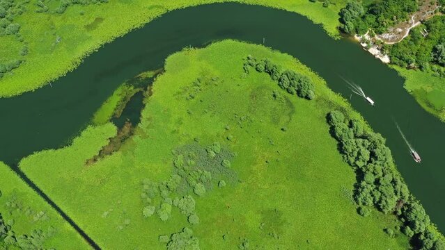 Aerial view of Rijeka Crnojevica - boats on beautiful river between mountains flowing into Skadar Lake, Montenegro, 4k