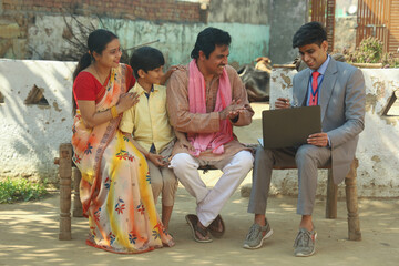 Happy rural Indian farmer villager family with the banker, insurance agent or a financial consultant. father and mother and son are happy to get the desired results. 